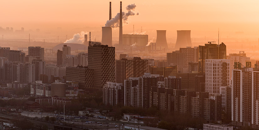 Aerial shot of hazy city featuring smoke stack.