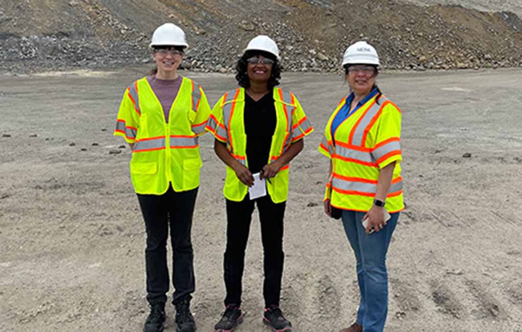 Three women standing in a field of gravel