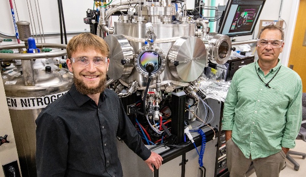 Two researchers standing next to lab equipment