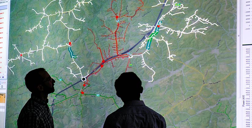 Photo of two researchers looking at a screen showing a distribution grid map