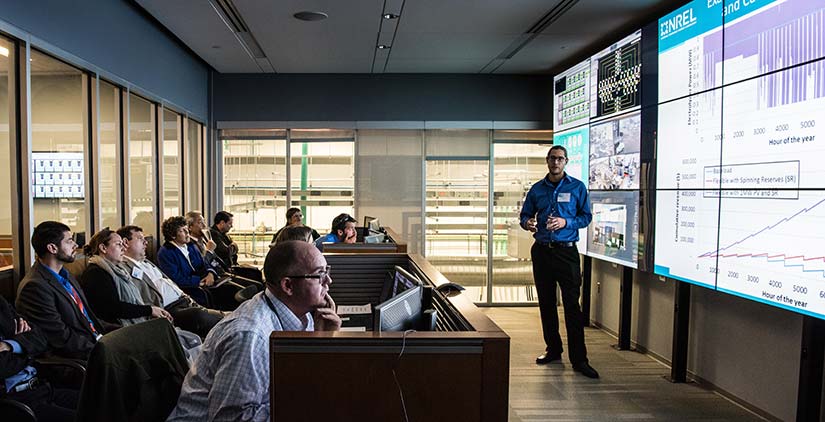 An NREL researcher presents on an electrolyzer grid integration demonstration in the control room of the Energy Systems Integration Facility.