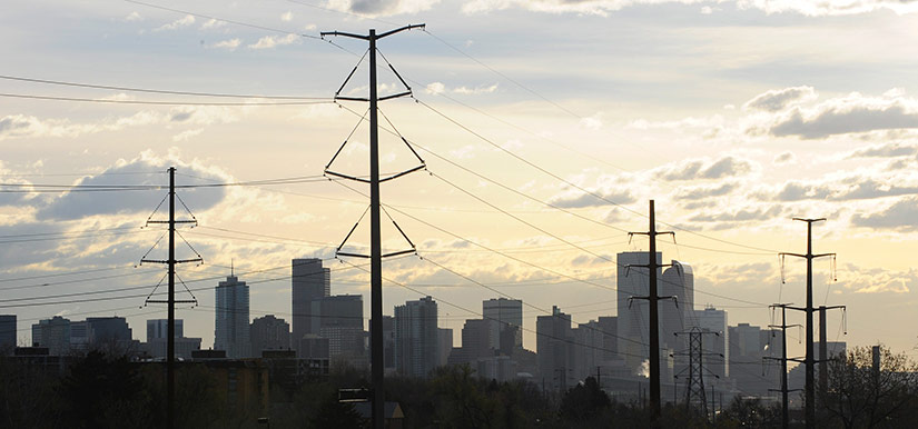 Photo of power lines with the Denver skyline in the background.