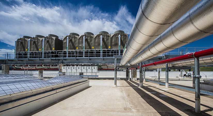 A photo of large metal pipes next to skylights on a roof.