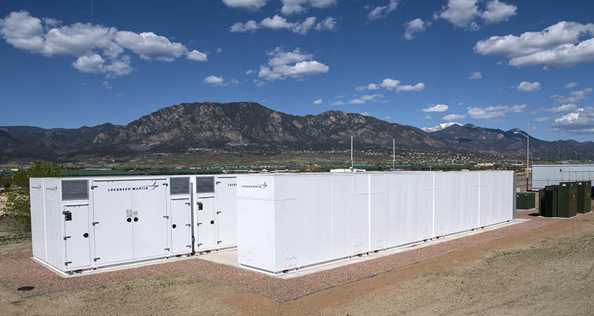 Two long containers on a field in front of mountains.