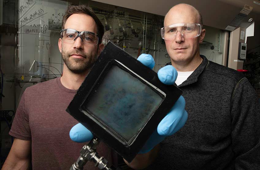 Two men hold up a window sample to the camera