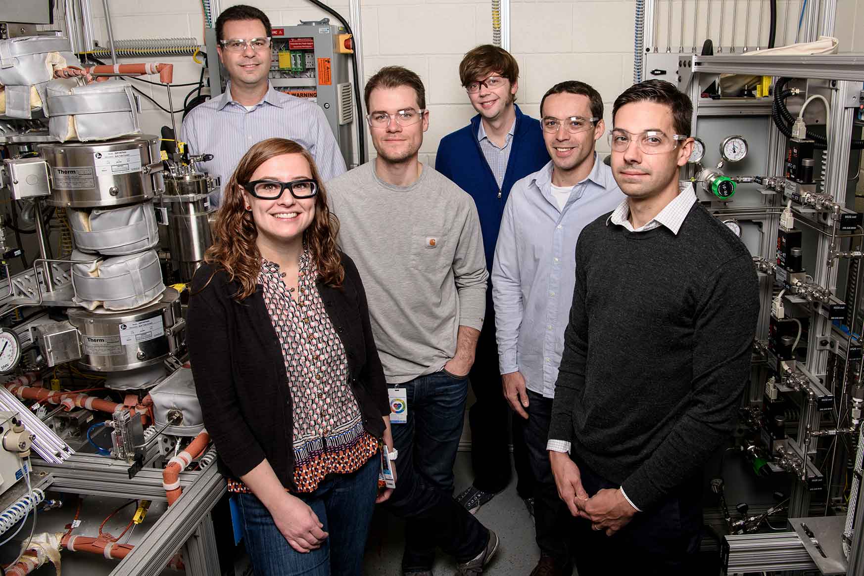 A group of people stand amid laboratory equipment.