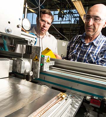 Two men work on batteries in a lab.