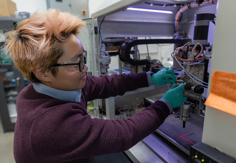 A researcher works in a glass box in a lab. 