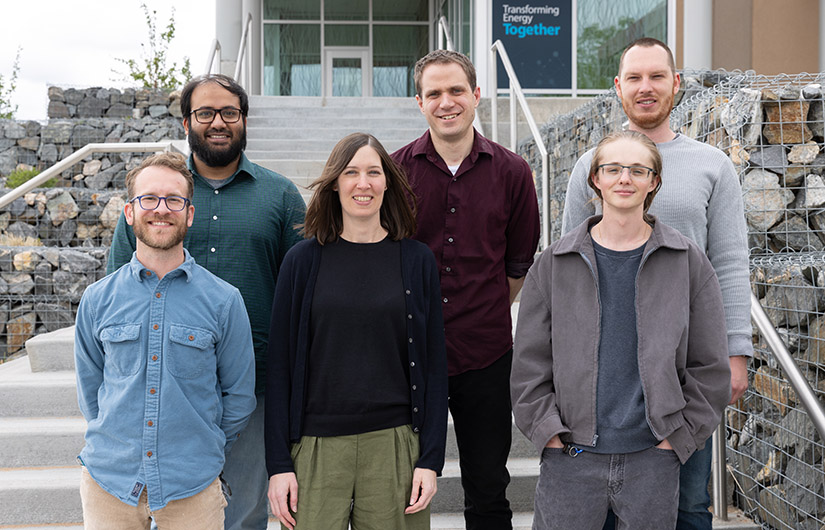 Six people stand on steps outside a building.