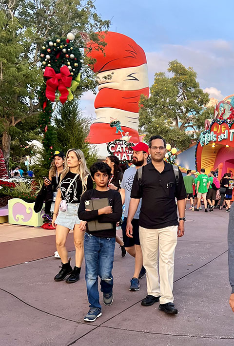 Man and boy walking through outdoor theme park.