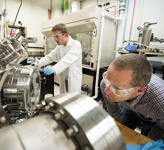 Scientists Andriy Zakutayev and Vladan Stevanovic examine laboratory equipment while conducting materials science research.