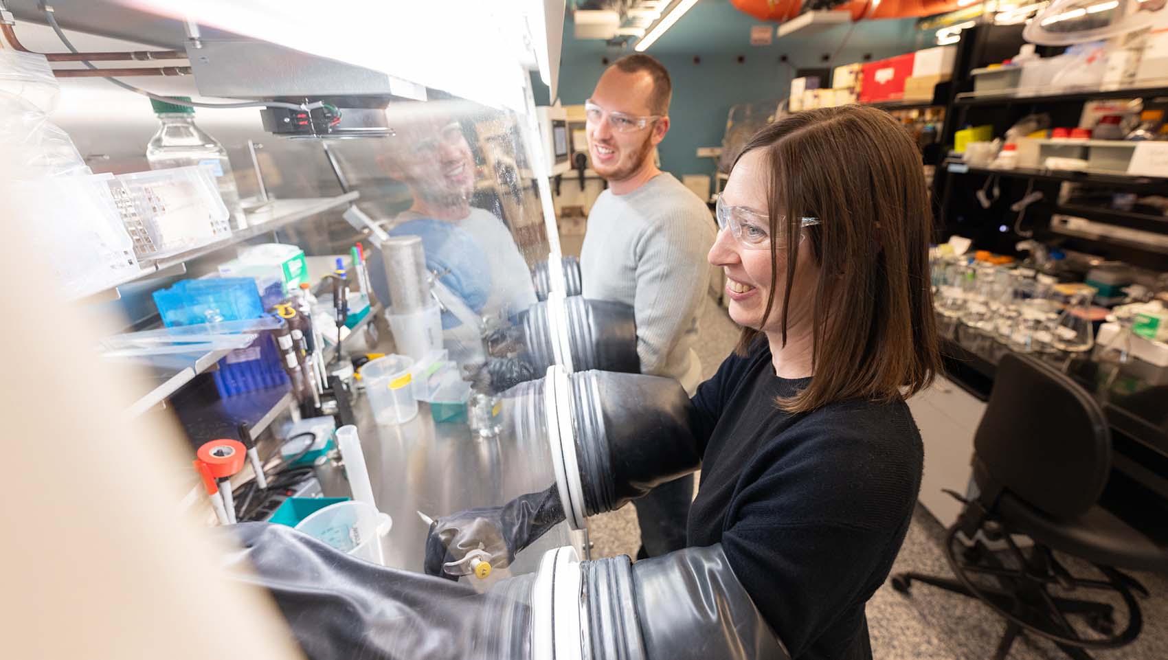 Two researchers with safety glasses work on an experiment in the lab.