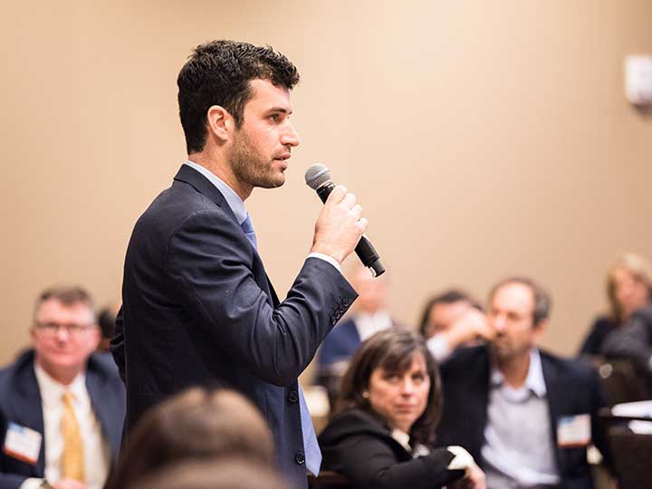 A man presenting with a microphone in a group of people.