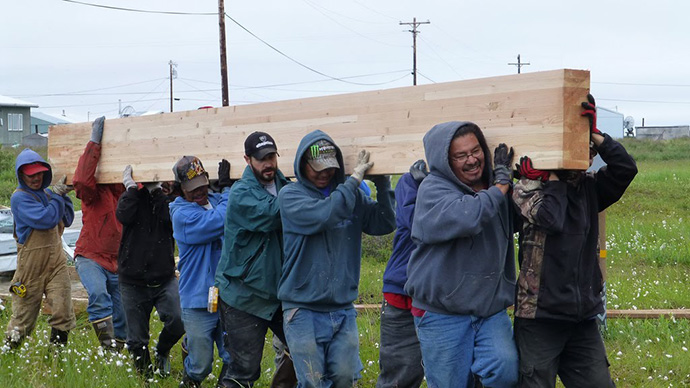 A group of people carrying a large peice of lumber.