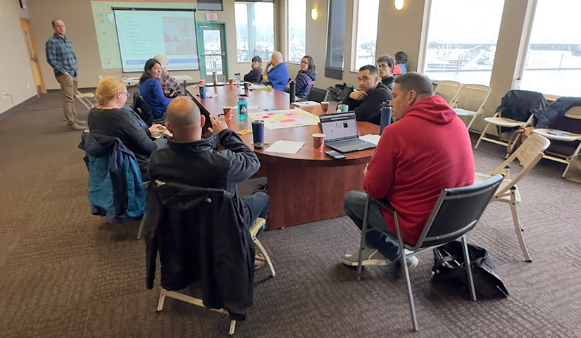 About 12 people sit around a conference table.