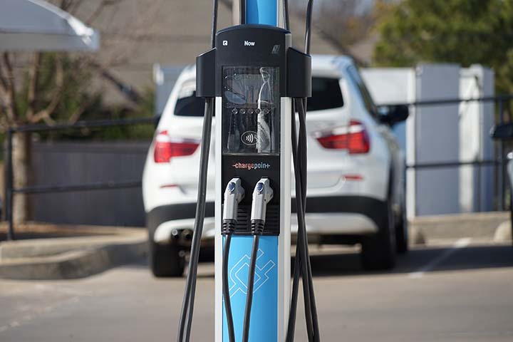 Chargepoint Level 2 electric vehicle supply equipment in the foreground and an electric vehicle in the background at BMW of Tulsa.