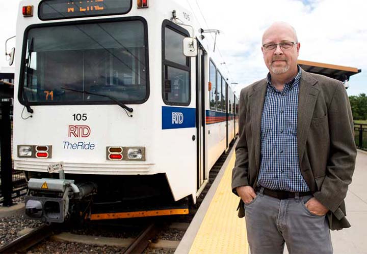 Man standing on platform next to RTD commuter train