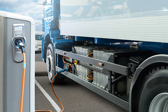 Heavy-duty freight truck at electric vehicle charging station.