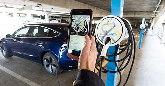 A hand taking a picture with a phone of an electric charging station. 