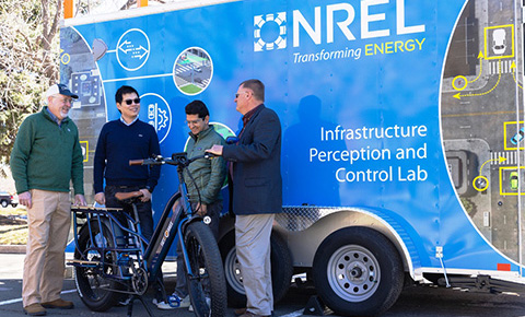 Four people behind an electric bicycle.