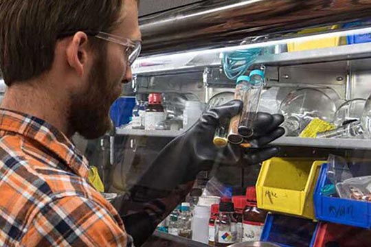 A man with rubber gloves holds three test tubes