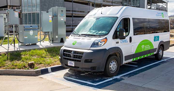 Photo of van parked in a designated spot next to several pieces of boxed equipment near a parking garage