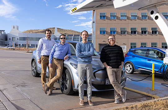 our people standing around a sedan at a charging station.