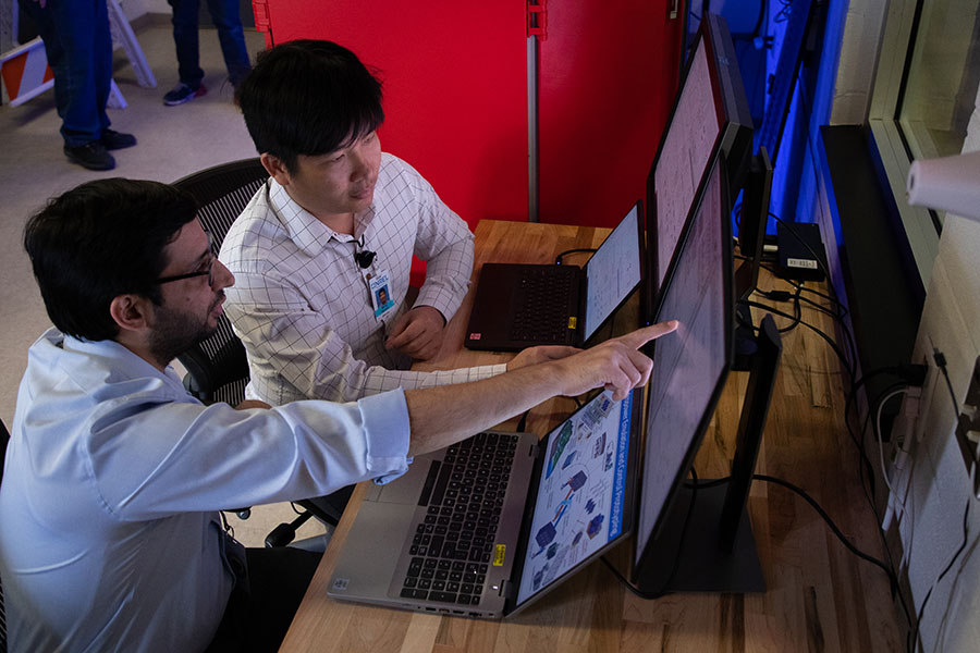 Two people look at data on a computer inside a laboratory.