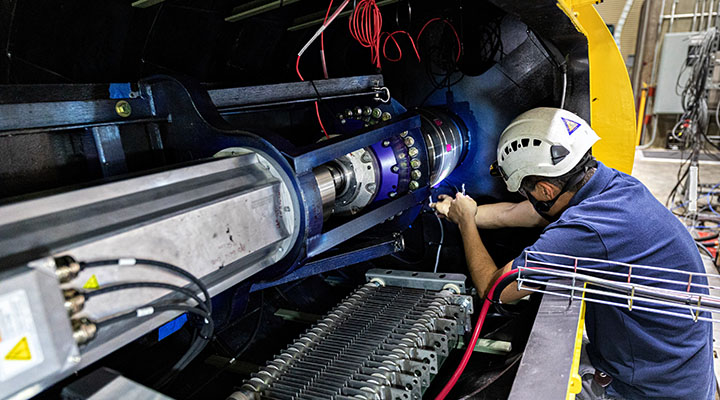 Researcher inside a large machine making adjustments